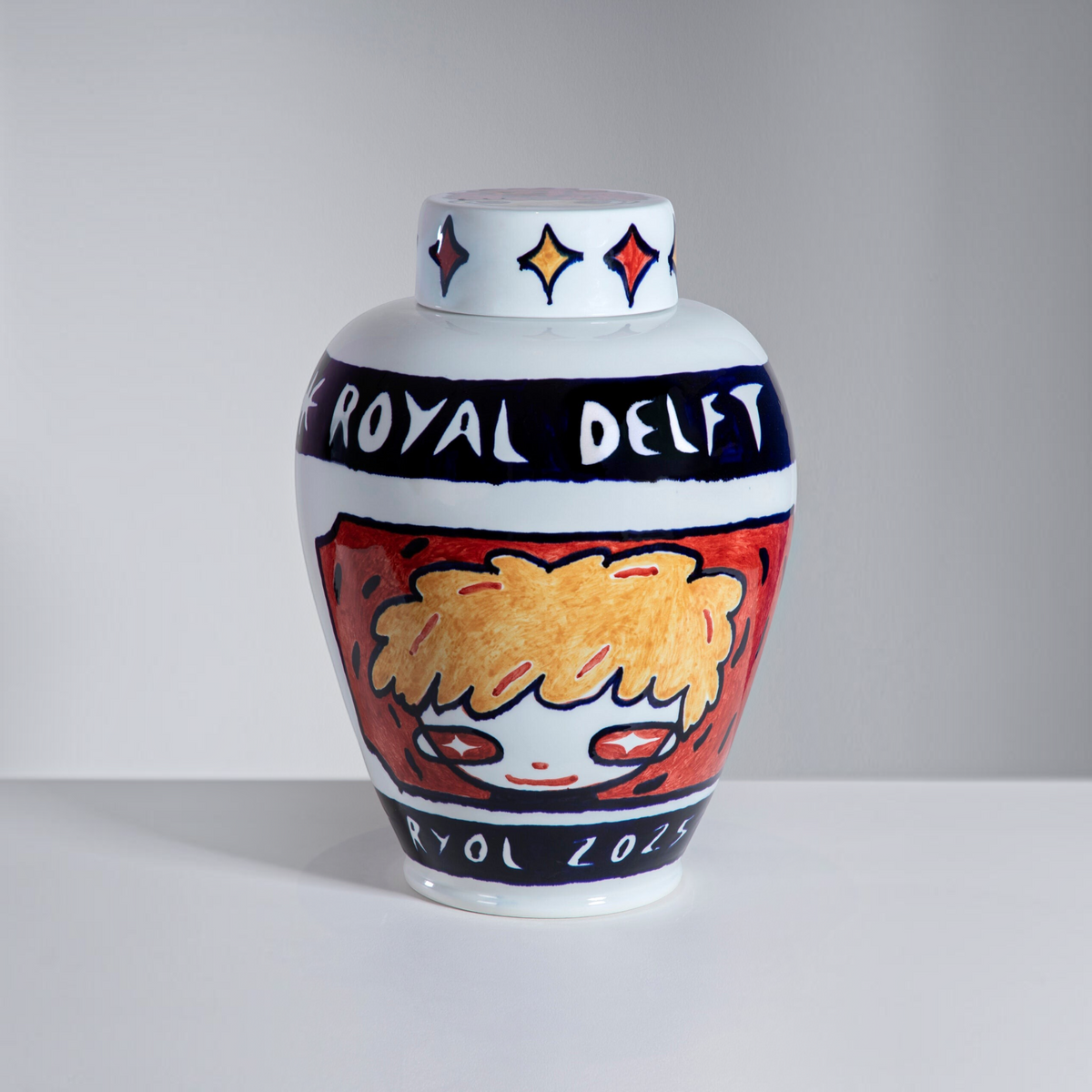 Royal Delft ceramic vase with removable lid, featuring hand-painted red and yellow stars and a stylized character.